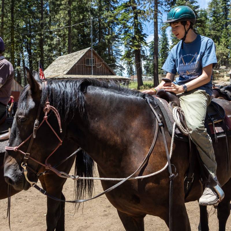Scout sitting on a horse at the Camp Hi-Sierra horse corral